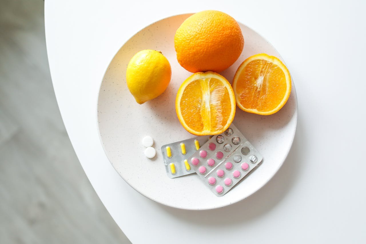 our-services-3 A plate of fresh citrus fruits and blister packs of pills, highlighting nutrition and healthcare.